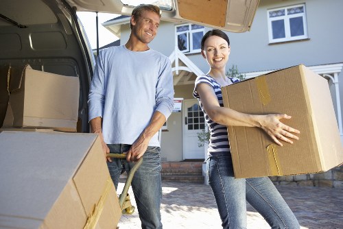 Professional movers carrying furniture through a narrow London staircase